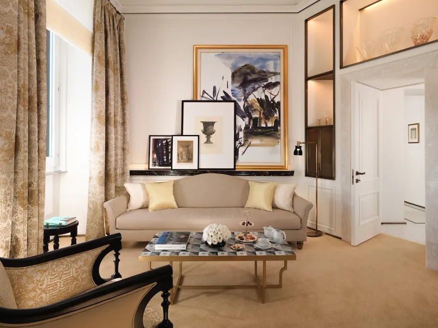 Classic suite living room with beige couch, living table and paintings on the wall