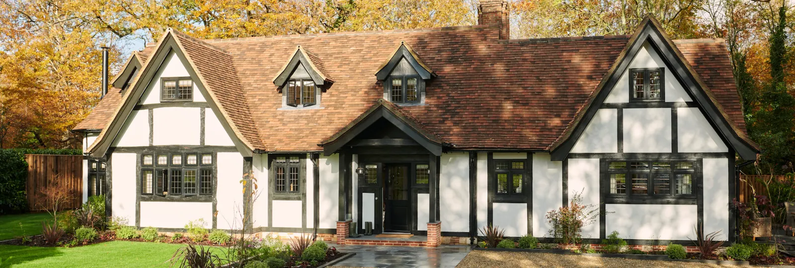 A charming house with a lush yard and autumn trees in the background.