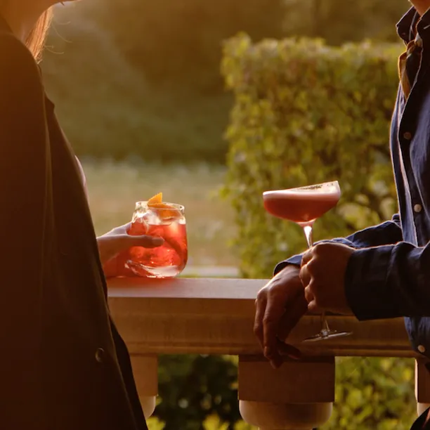 Guests enjoying cocktails on the terrace at sunset at Coworth Park ,Ascot