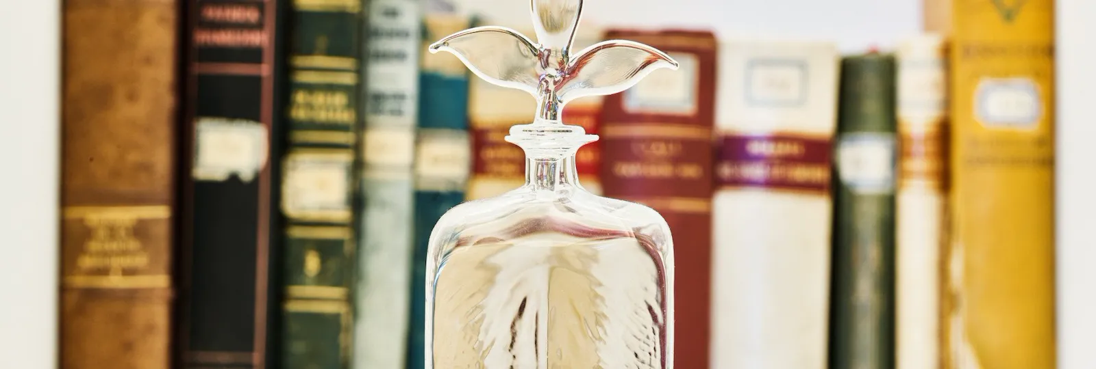 Glass bottle and books in the background inside Classic Suite at Hotel Eden, Rome