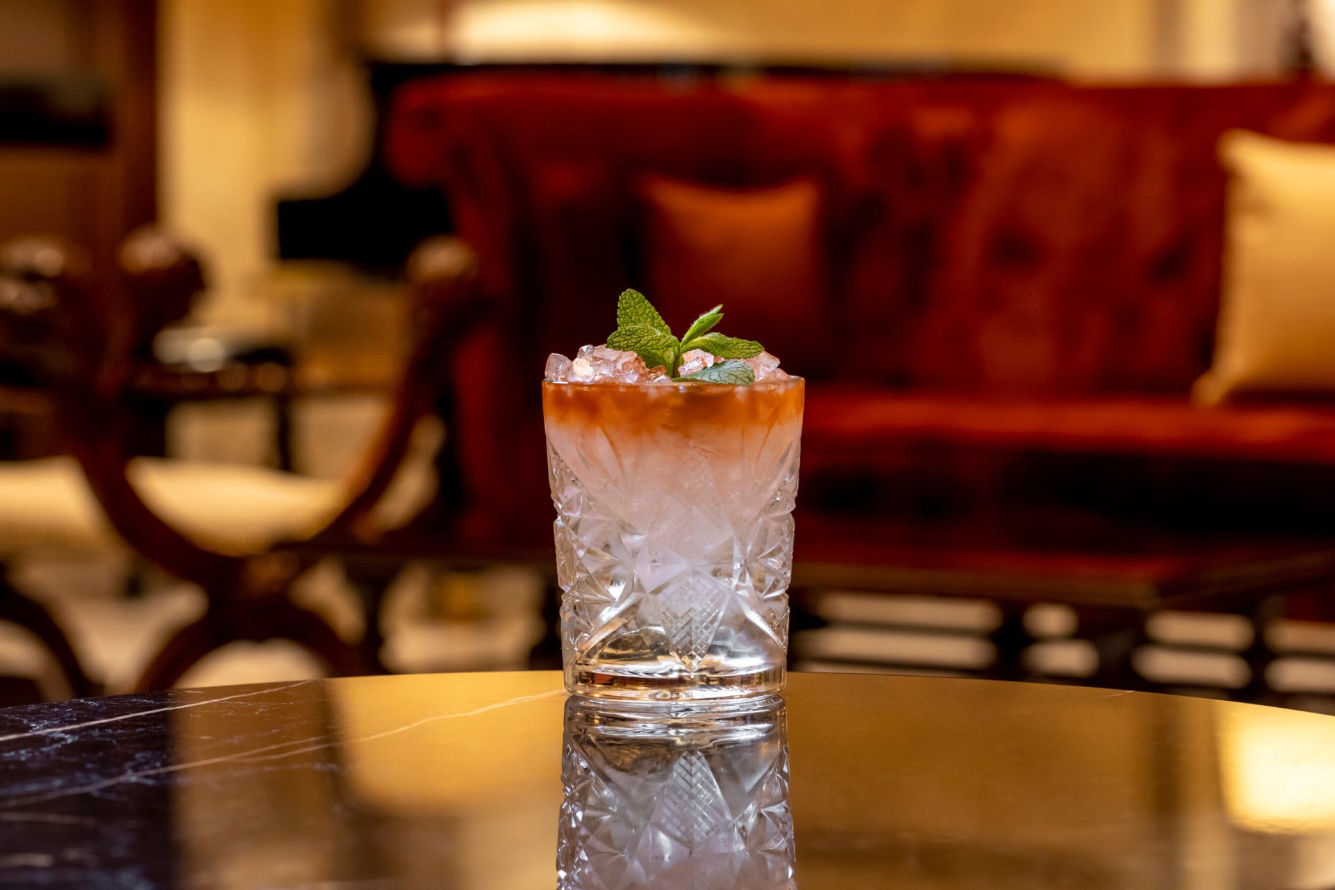 Cocktail with orange hue and mint decoration at La Libreria at Hotel Eden, Rome