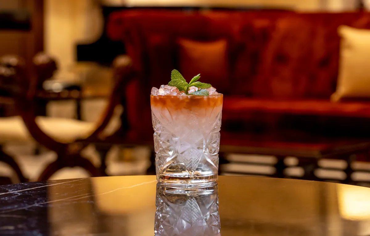 Cocktail with orange hue and mint decoration at La Libreria at Hotel Eden, Rome