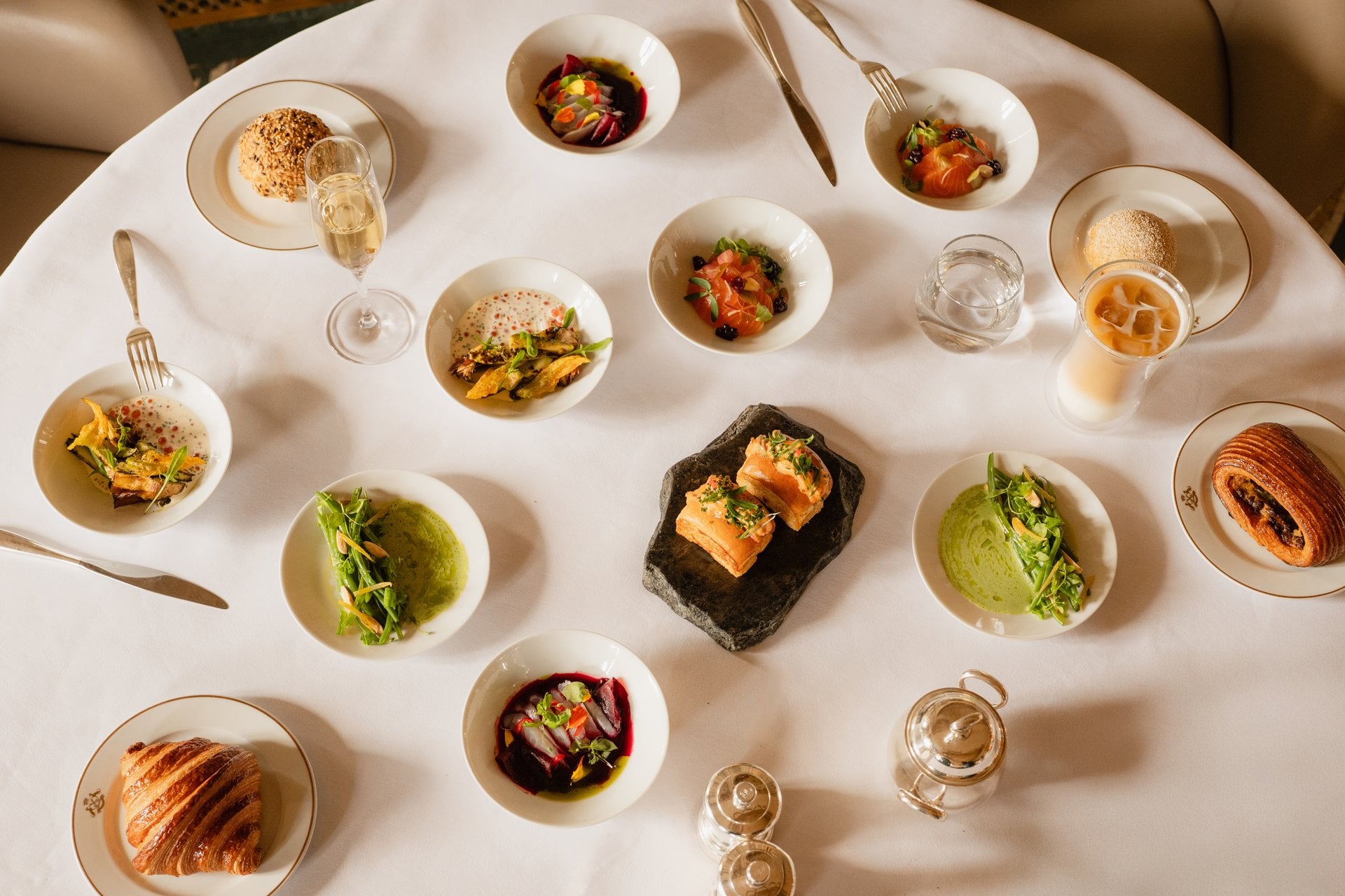 This visual shows the brunch menu of restaurant Le Meurice Alain Ducasse.  There are several sweet and savory dishes on a white table cloth.