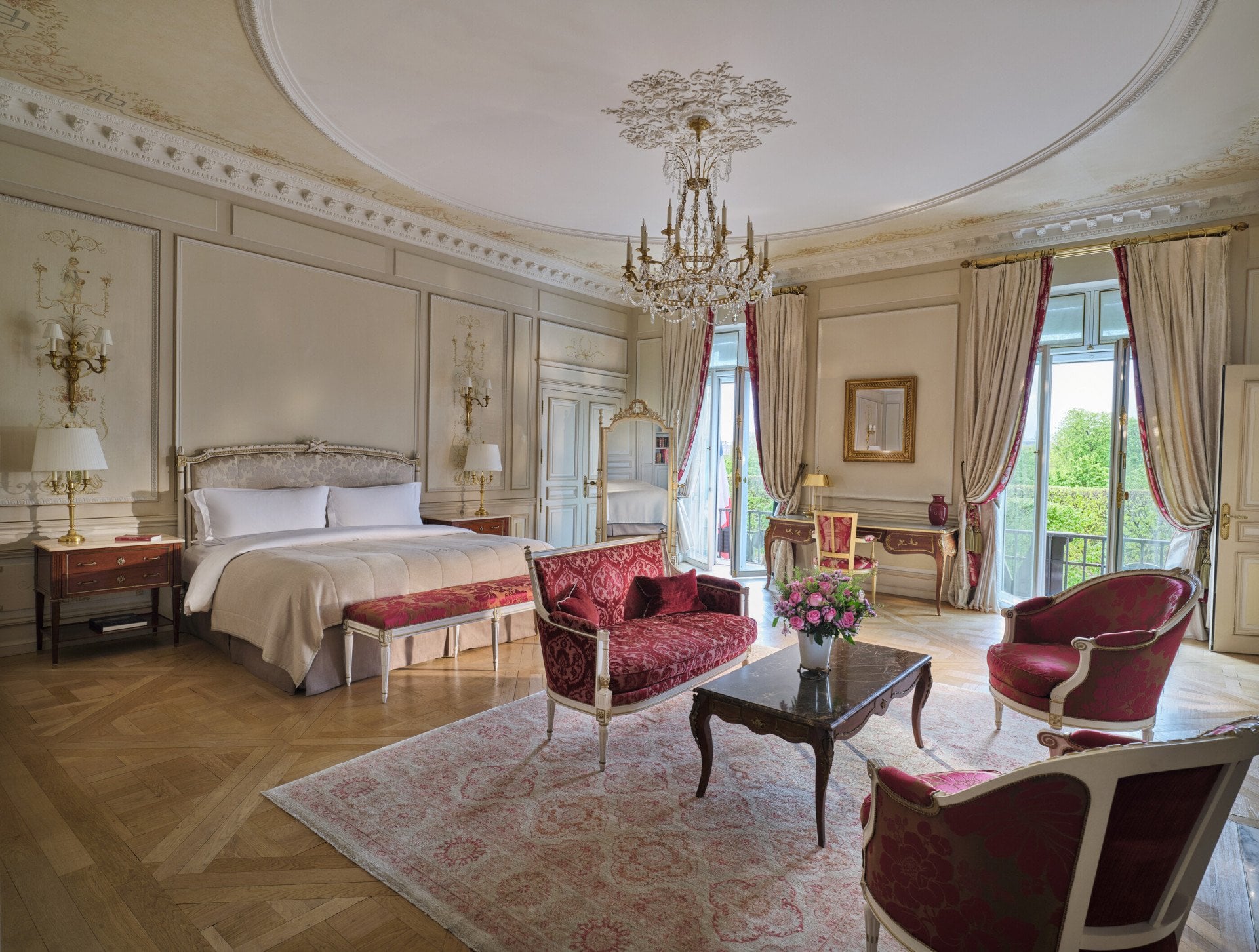 Large view of the Presidential Suite Dali with in first plan the furnitures of a living room like the couch, the rug and the chairs, and in the background the bed and the mirror, at Le Meurice, Paris