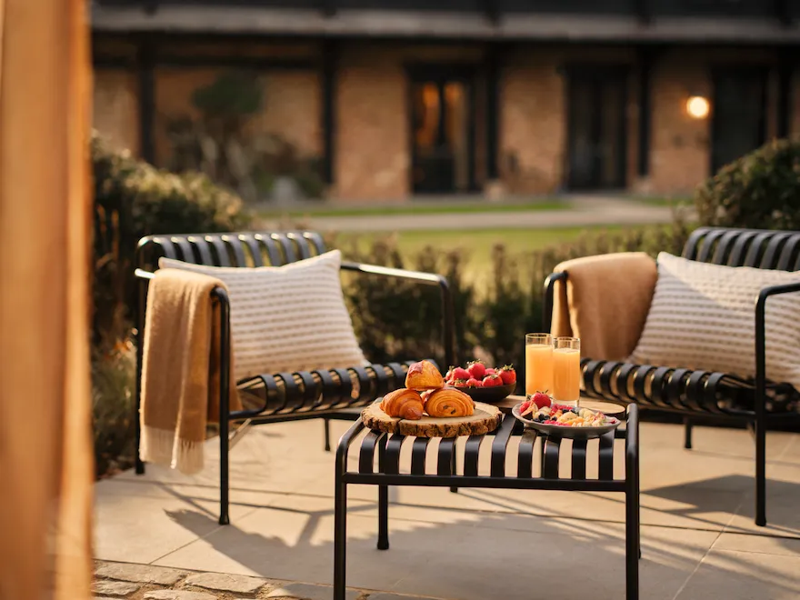 Outdoor breakfast with croissants, fresh fruit, and orange juice on a private terrace at Coworth Park, Ascot