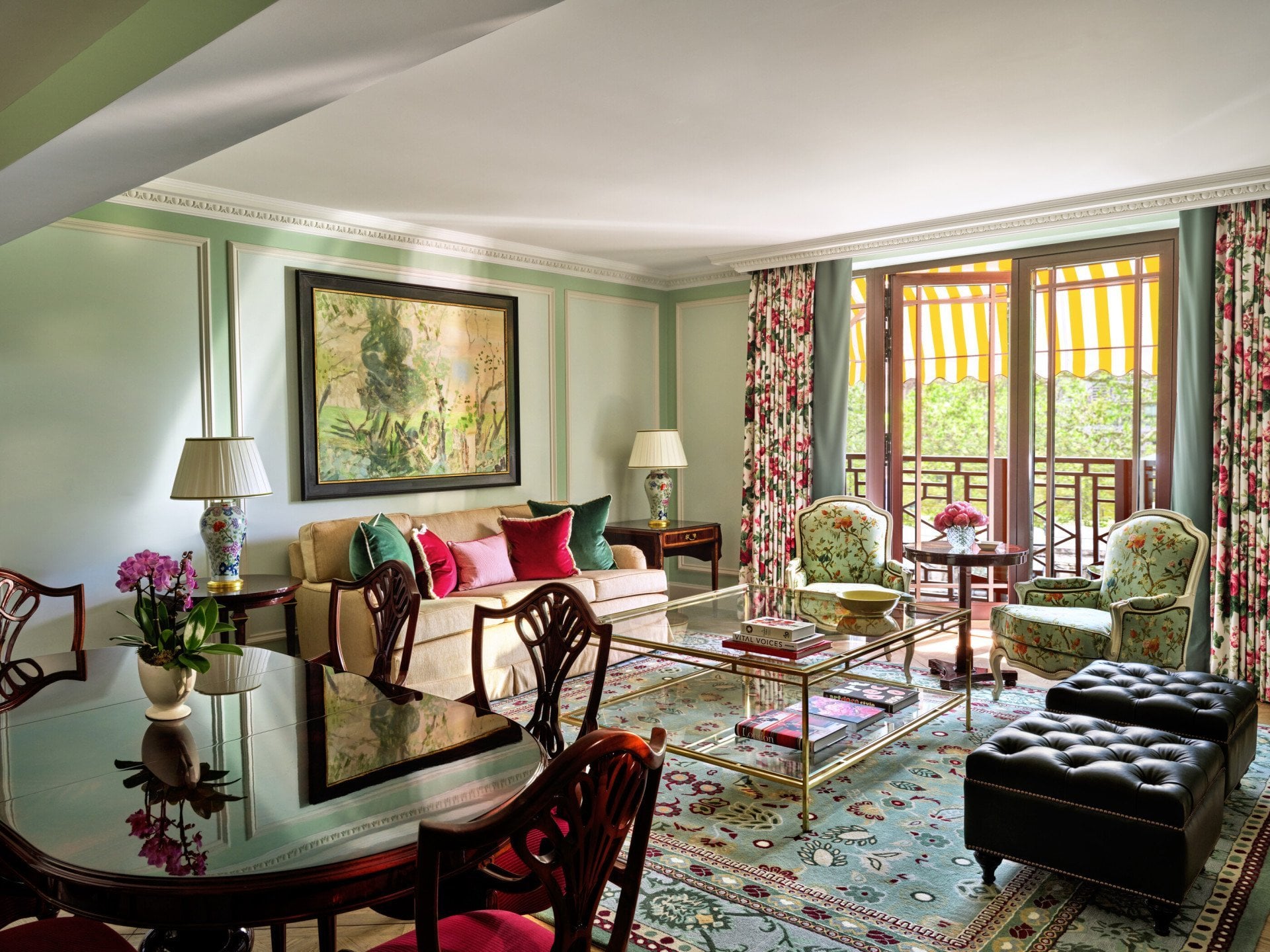 The Belgravia Suite with elegant green and red tones, a comfortable lounge seating area, dining space and a Juliet balcony offering views across Hyde Park and Park Lane.