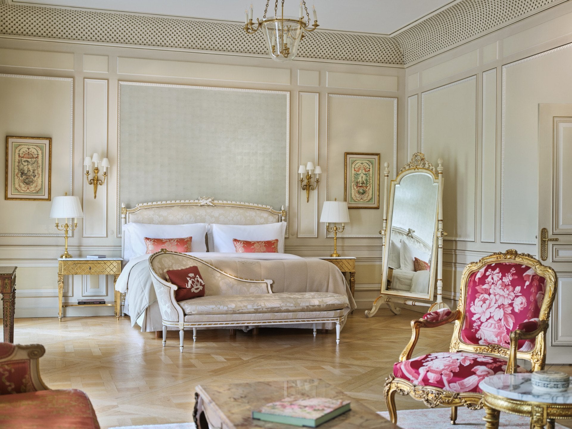 Large view of a Versailles Suite with the chair and the table in first plan and the couch, the bed and the mirror in the background, at Le Meurice, Paris