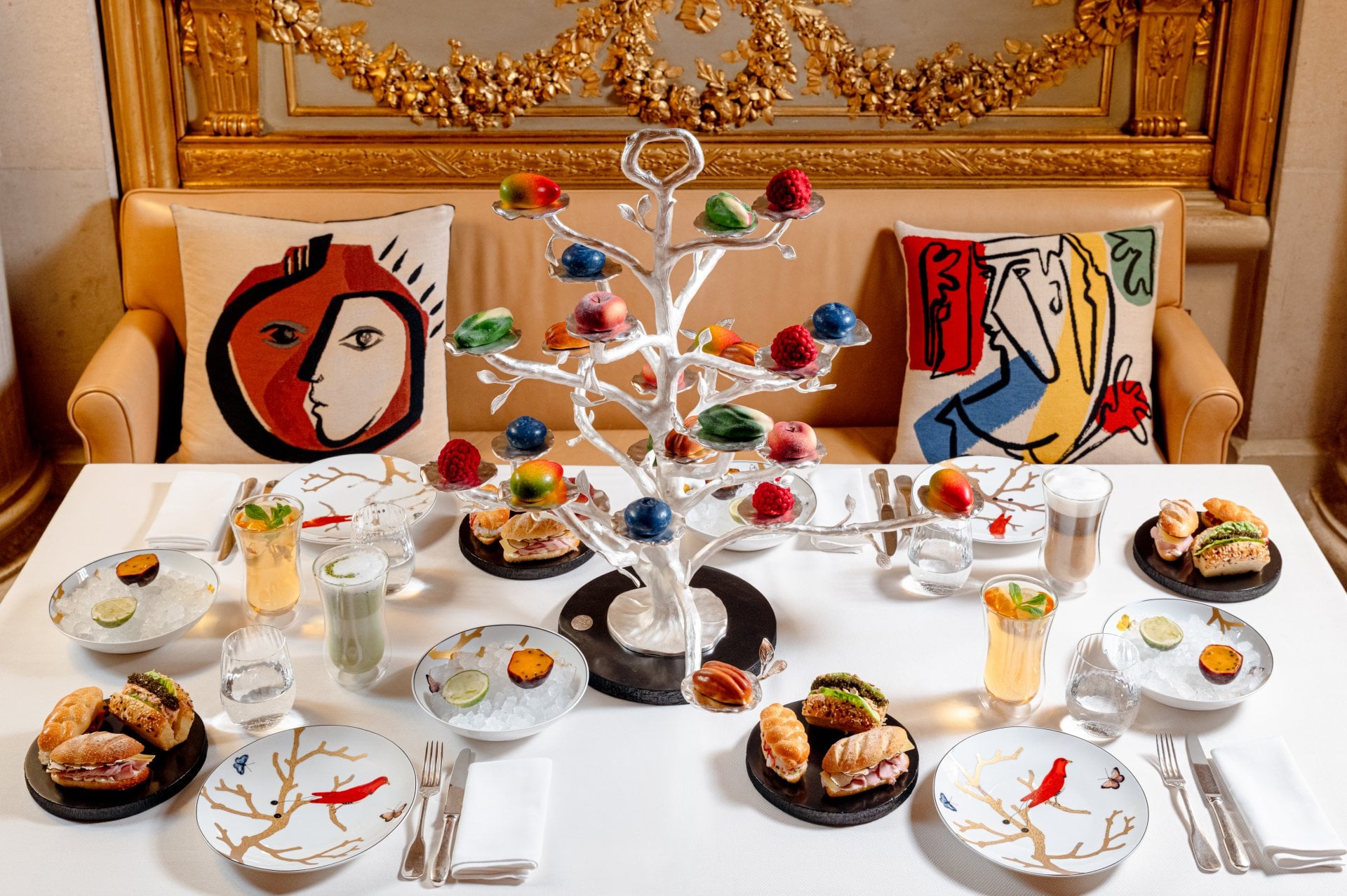 Elegant dining table with colorful cake, drinks, and a decorated white tree centerpiece.