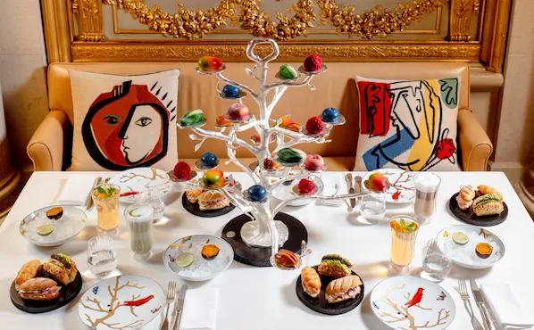 Elegant dining table with colorful cake, drinks, and a decorated white tree centerpiece.