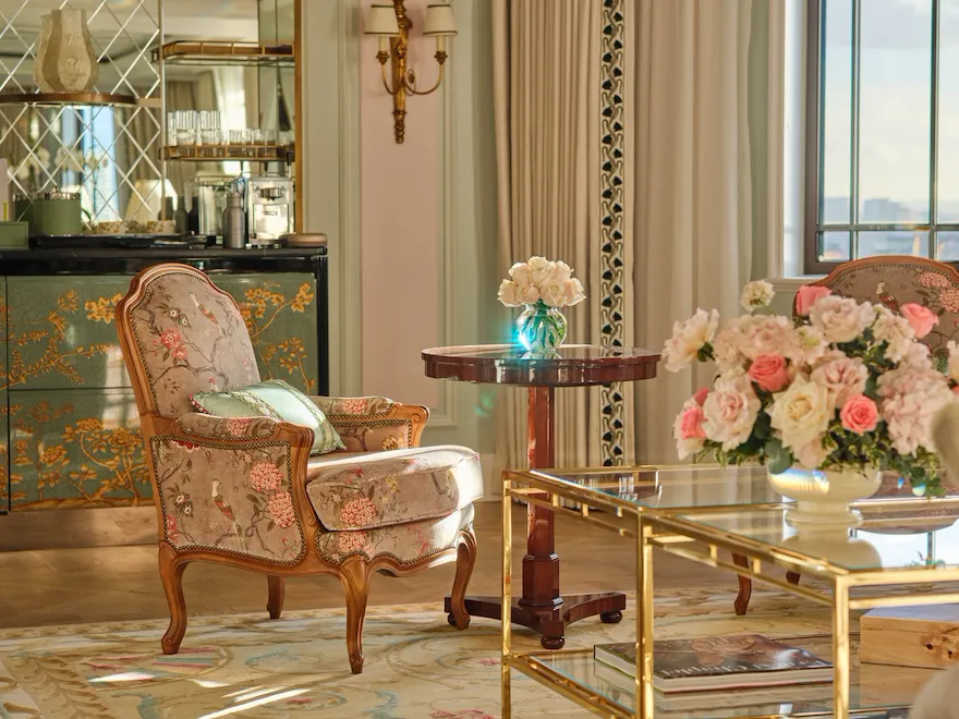 Elegant living room with a floral arrangement, sunlight, vintage furniture, and classic decor.