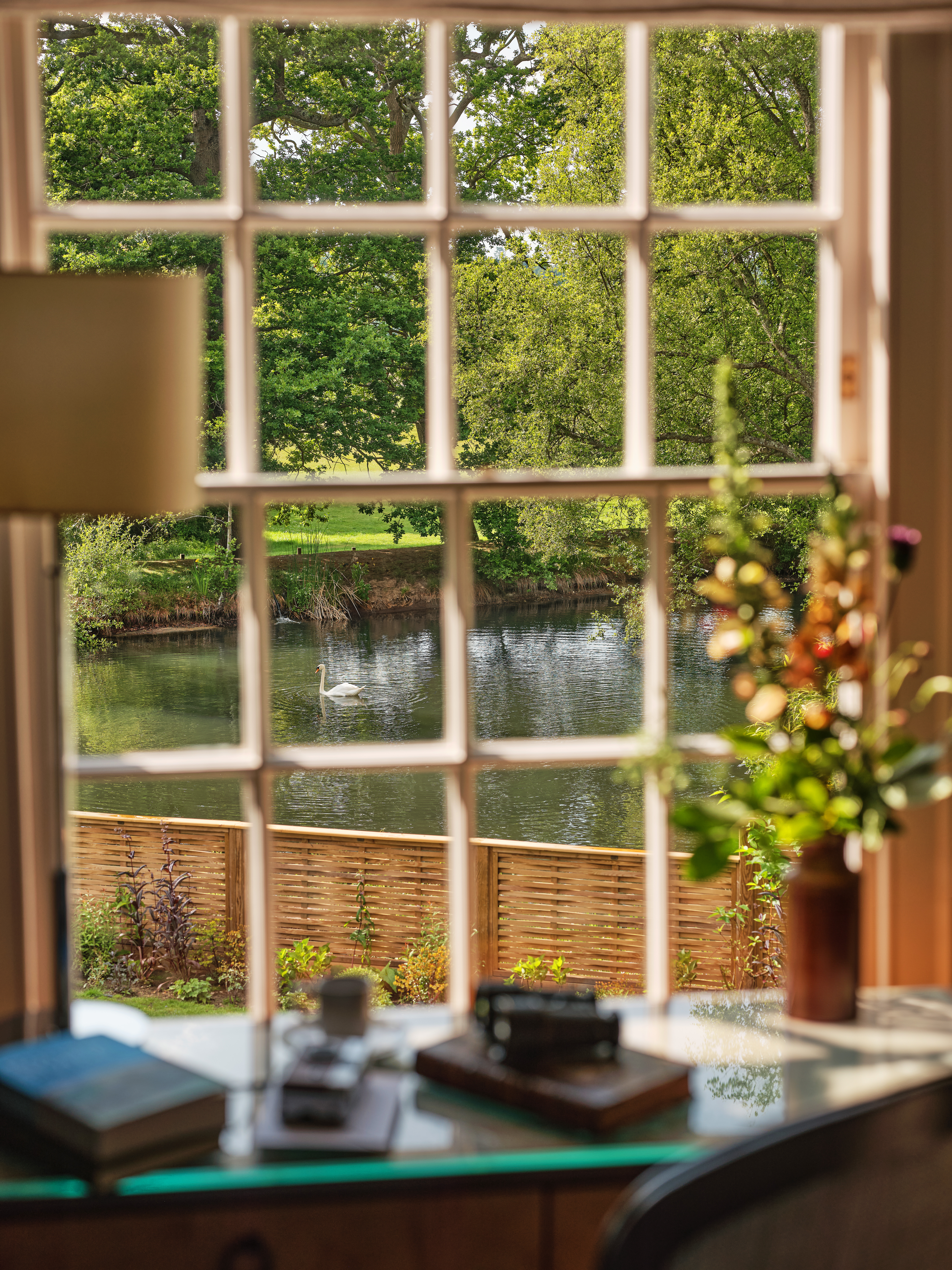 View of the lake and swan through the window of the Dower House at Coworth Park