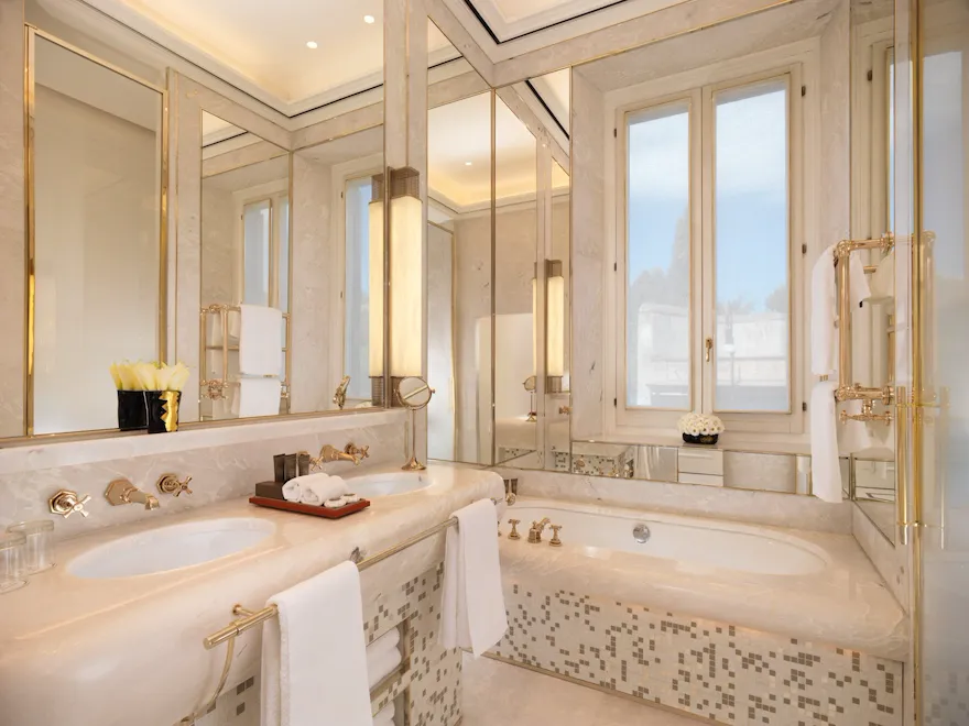 White marble bathroom of classic room with double sinks and bathtub at Hotel Eden, Rome
