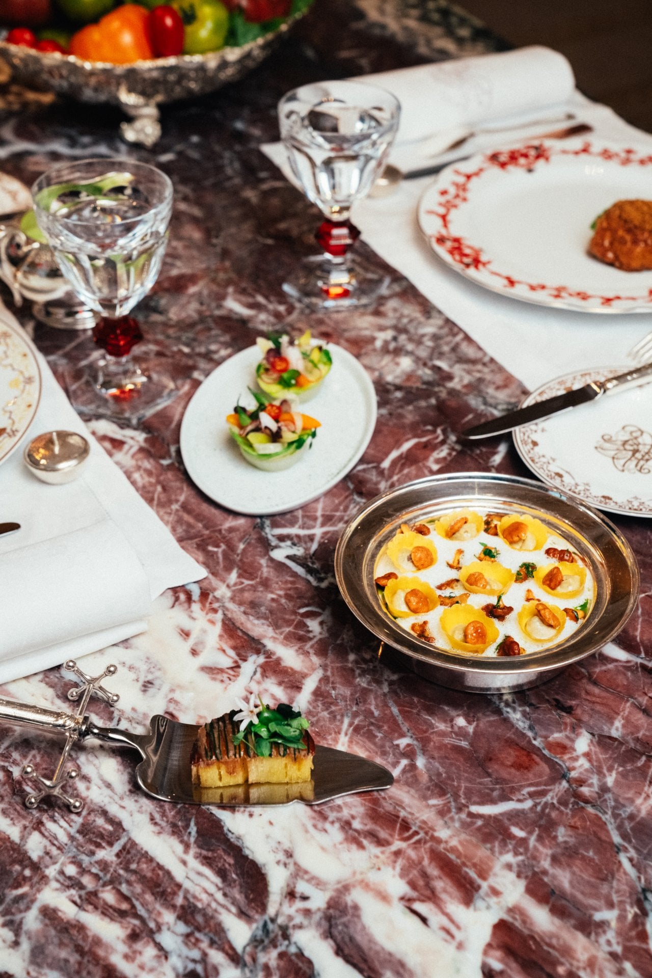 Table setting with dishes, glasses, cutlery, and decorated plates on a marble surface.