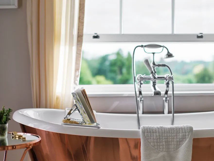 Copper bathtub with window nearby open with countryside view of Coworth Park, Ascot