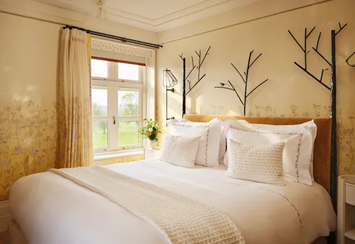 Bedroom with nature-inspired four-poster bed and garden views in the Gardeners suite at Coworth Park, Ascot