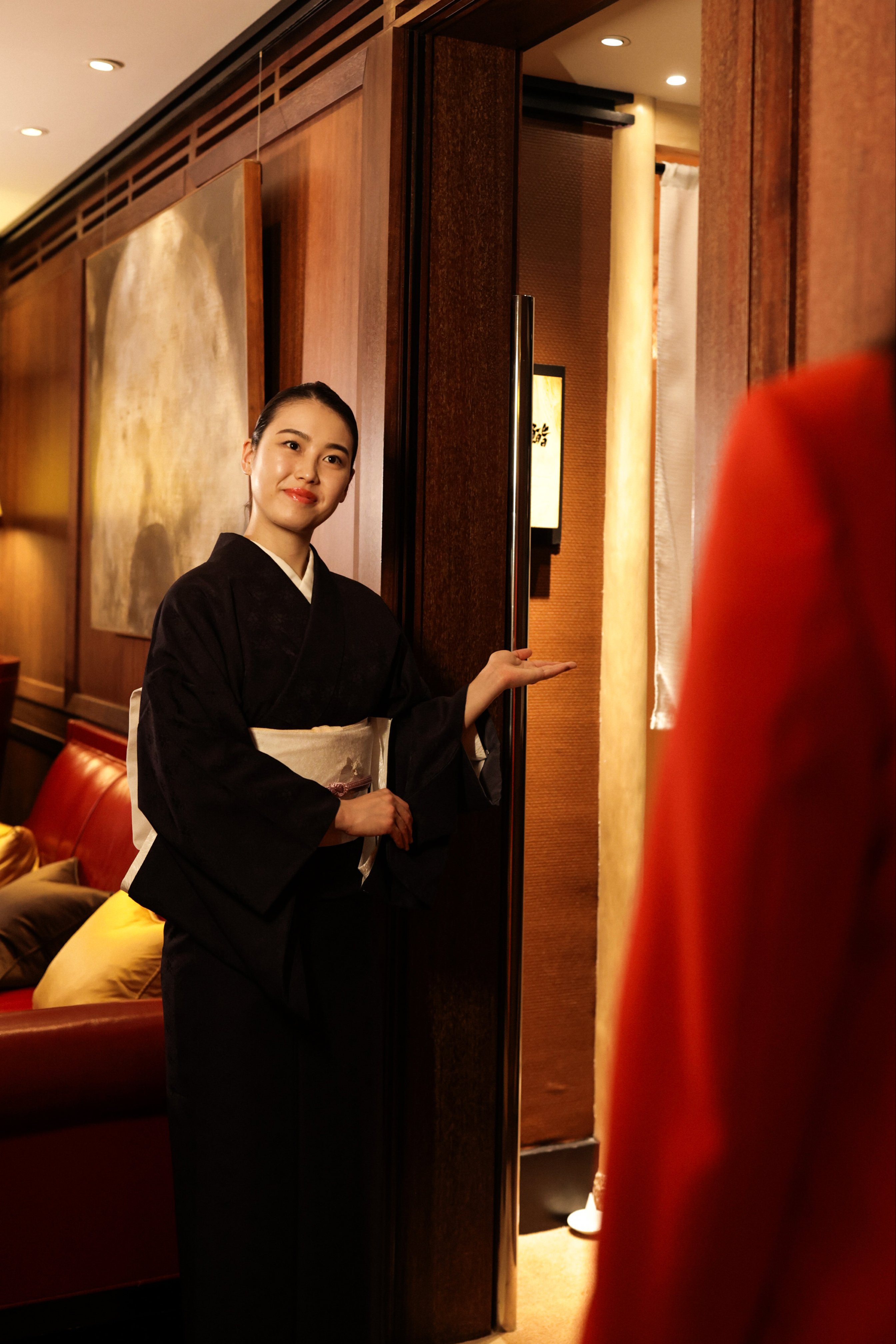 Hostess in traditional black kimono welcoming guests at the entrance of Sushi Kanesaka, 45 Park Lane