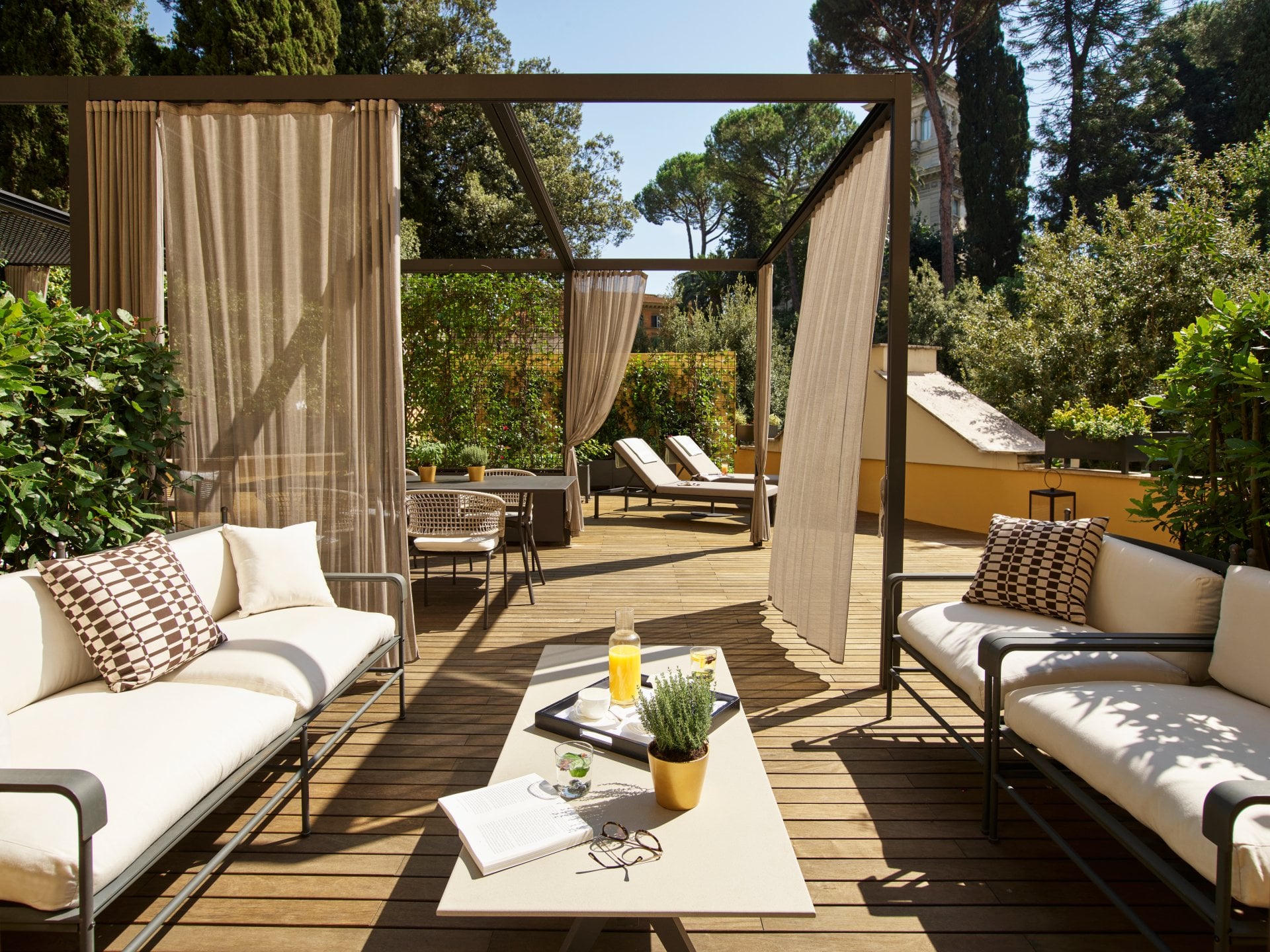 Outdoor patio with sofas, curtains, and sunshine creating a relaxing, peaceful atmosphere